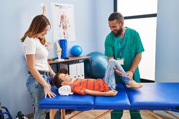 Family having physiotherapy session stretching child legs at rehab clinic