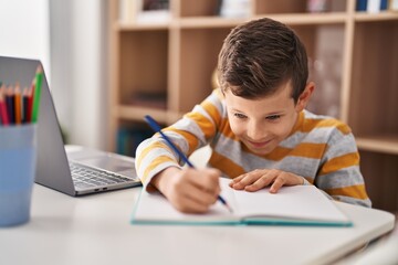 Blond child studying sitting on table at home