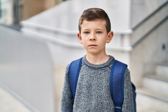 Blond child student standing with serious expression at school