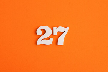White wooden number 27 on eva rubber orange background