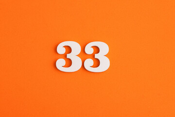 White wooden number 33 on eva rubber orange background