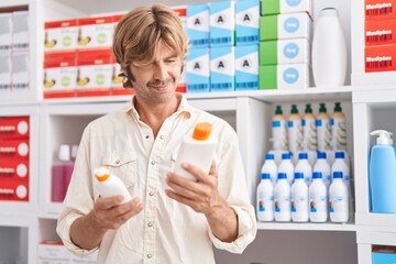 Young man customer holding sunscreen bottles at pharmacy