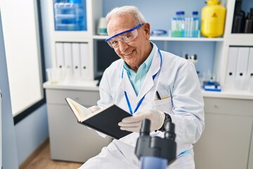 Naklejka na ściany i meble Senior man wearing scientist uniform reading book at laboratory