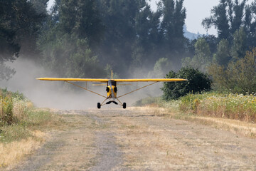 piper cub taking off on gravel strip with dust flying - obrazy, fototapety, plakaty