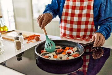 Senior man cooking at kitchen