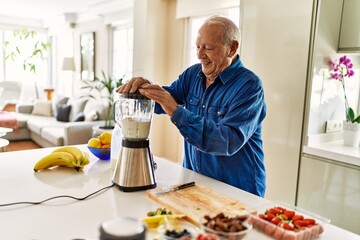 Senior man smiling confident shaking blender at kitchen