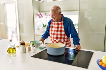 Senior man smiling confident cooking spaghetti at kitchen