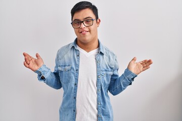 Young hispanic man with down syndrome wearing casual denim jacket over white background shouting...