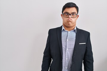 Young hispanic man with down syndrome wearing business style puffing cheeks with funny face. mouth inflated with air, crazy expression. - obrazy, fototapety, plakaty