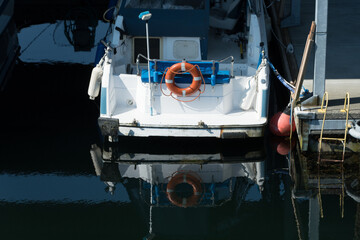 Obraz na płótnie Canvas Reflections of white boat with red lifesaver docked at Edmonds marina