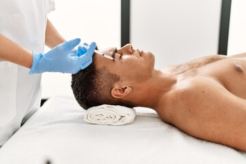 Fototapeta na wymiar Young hispanic man relaxed having antiaging treatment at beauty center