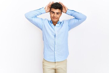 Young hispanic man wearing business shirt standing over isolated background doing bunny ears gesture with hands palms looking cynical and skeptical. easter rabbit concept.