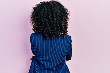 Young african american woman wearing business clothes and glasses standing backwards looking away...
