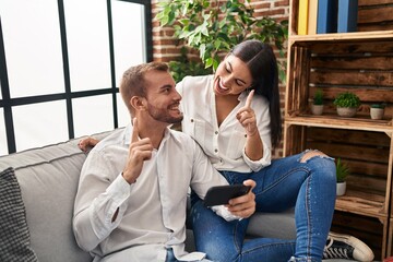 Man and woman couple smiling confident using smartphone at home