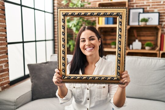 Young hispanic woman holding empty frame smiling with a happy and cool smile on face. showing teeth.