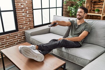 Young hispanic man smiling confident watching tv at home