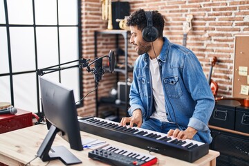 Young arab man musician singing song playing piano keyboard at music studio