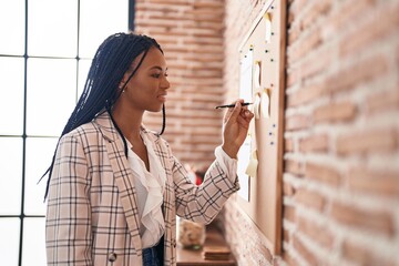 African american woman business worker writing on cork board at office