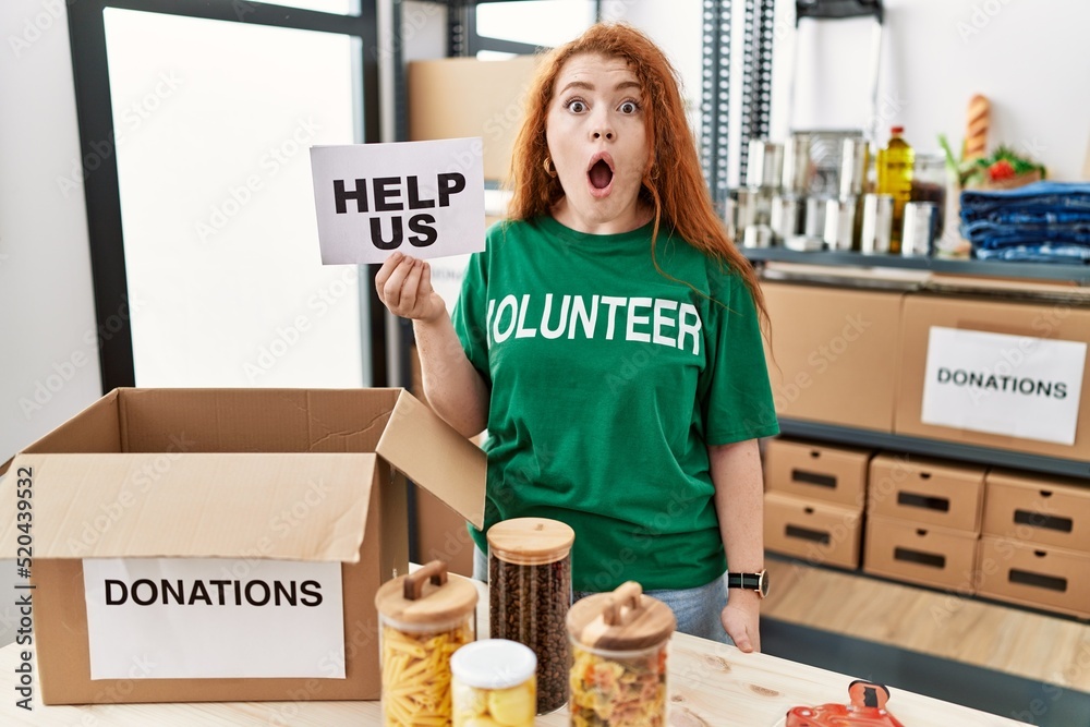 Canvas Prints young redhead woman wearing volunteer t shirt holding help us banner scared and amazed with open mou