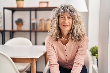 Middle age woman smiling confident sitting on chair at home