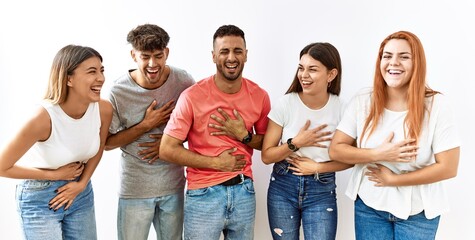 Group of young friends standing together over isolated background smiling and laughing hard out loud because funny crazy joke with hands on body.