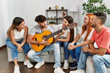 Group of young friends having party playing guitar at home.