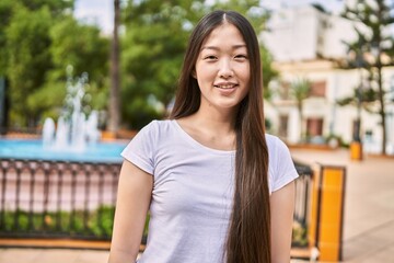 Young chinese girl smiling happy standing at the city.