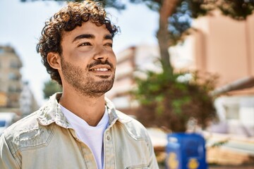 Handsome hispanic man with beard smiling happy outdoors on a sunny day