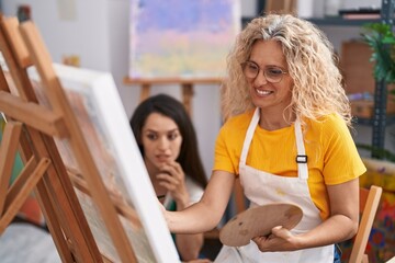 Two women artists smiling confident drawing at art studio