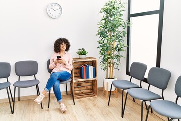 Young middle east woman using smartphone sitting on chair at waiting room