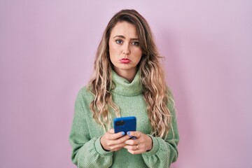 Fototapeta premium Young caucasian woman using smartphone typing message depressed and worry for distress, crying angry and afraid. sad expression.