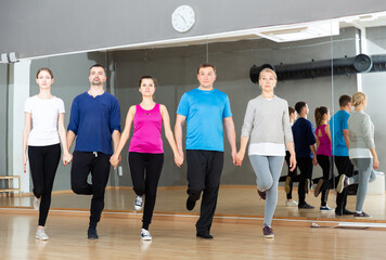 Positive adults forming line while rehearsing traditional Irish stepdance in dance studio