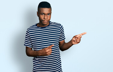 Young african american man pointing with fingers to the side skeptic and nervous, frowning upset...