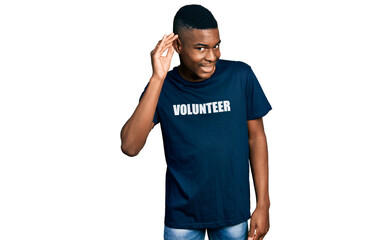 Fototapeta premium Young african american man wearing volunteer t shirt smiling with hand over ear listening an hearing to rumor or gossip. deafness concept.