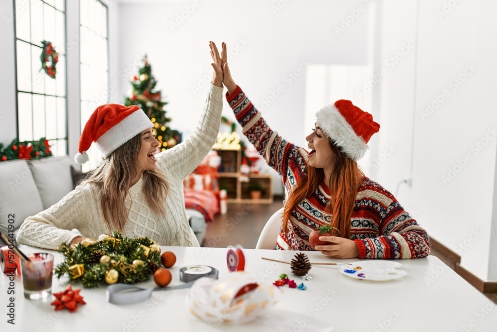 Poster Woman couple making handmade christmas decoration high five raised up hands at home