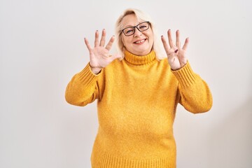 Middle age caucasian woman wearing glasses standing over background showing and pointing up with...