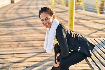 Middle age hispanic woman resting after working out at promenade