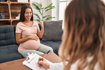 Young pregnant woman at therapy session screaming proud, celebrating victory and success very...