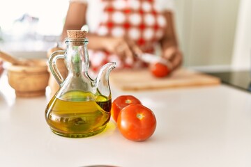 Hispanic brunette woman cooking cutting tomatoes at the kitchen