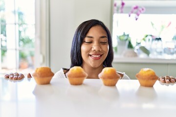 Hispanic brunette woman looking to muffins at the kitchen