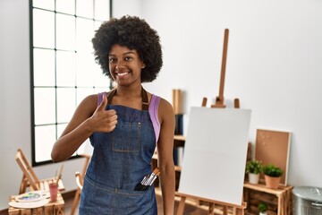 Young african american woman with afro hair at art studio doing happy thumbs up gesture with hand....