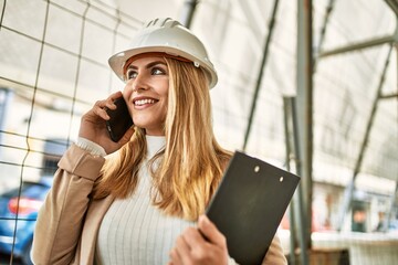 Young blonde woman smiling confident talking on the smartphone at street