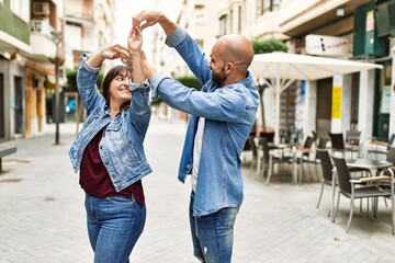 Young hispanic couple smiling happy dancing at the city.