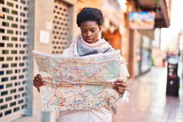 African american woman smiling confident holding city map at street