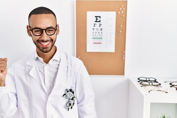 African american optician man standing by eyesight test dancing happy and cheerful, smiling moving casual and confident listening to music