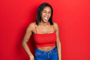 Young african american girl wearing casual style with sleeveless shirt winking looking at the...