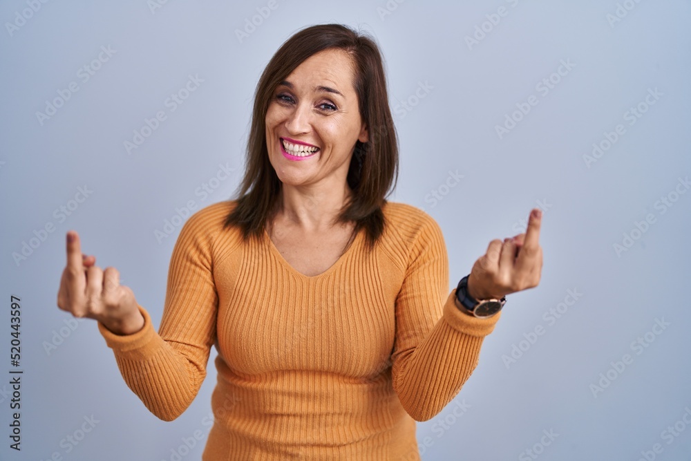 Sticker Middle age brunette woman standing wearing orange sweater showing middle finger doing fuck you bad expression, provocation and rude attitude. screaming excited