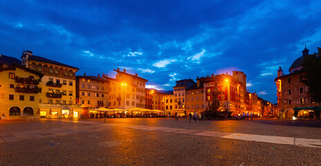 View of busy central city square Piazza Duomo in autumn evening, Trento, Italy.