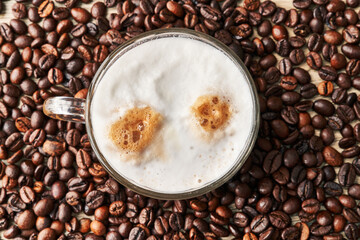  One cup of coffee with milk and coffee beans on wooden surface