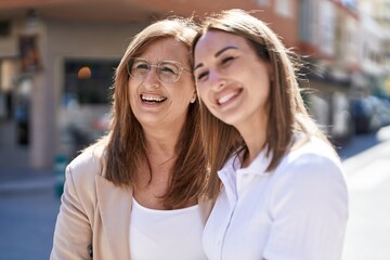 Mother and daughter smiling confident standing together at street